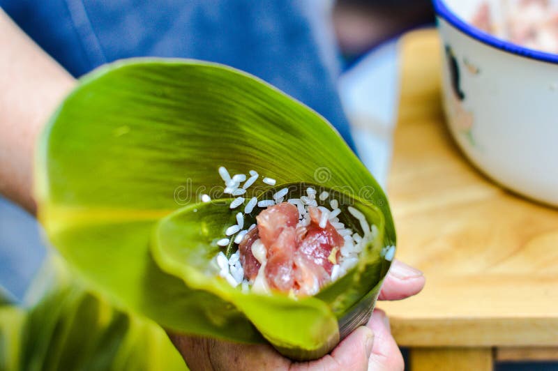 拿着叶子被填装的黏米饭&猪肉的手做zongzi 图库摄影图片