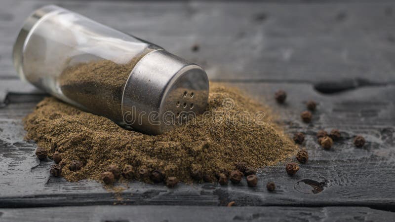 碎椒从在一张木桌上的一个玻璃瓶子倒