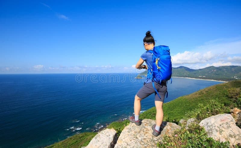 背包徒步旅行者享受在海边山岩石的看法