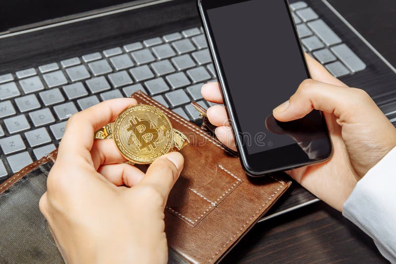 拿着智能手机和bitcoin的手特写镜头 隐藏货币概念 财务往来 图库摄影