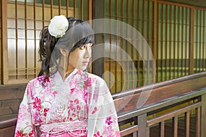 Asian woman wearing a yukata in front of Japanese style windows