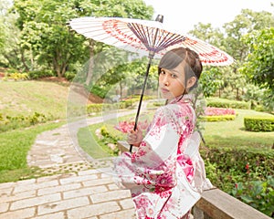 Asian woman wearing a yukata and holding an umbrella in Japanese