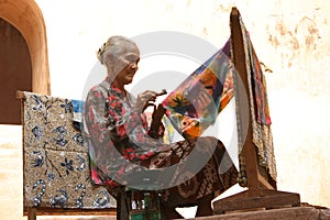 Elderly woman making traditional batik