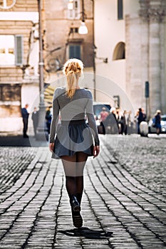 Girl walking on the street in the city wearing a skirt. Back.