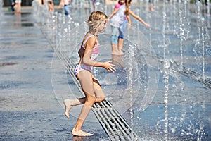 Little girl running among fountains" border="0