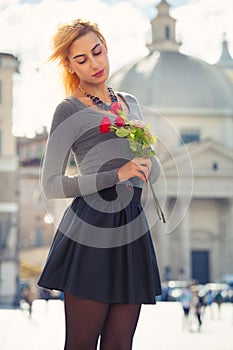 Young girl in love. Blonde teenager with roses in hand.