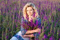 Blond woman with purple flowers gorgeous young in blooming field holding Royalty Free Stock Photo