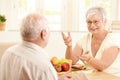 Elderly wife chatting to husband at breakfast