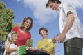 Family Around Grill In Garden