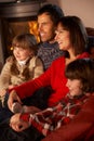 Family Relaxing Watching TV By Cosy Log Fire