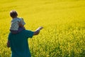 Father and son looking on rapeseed field on summer day