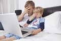 Father and son watching scary movie on laptop in bed