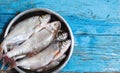 Fresh fish in iron bowl on a wooden background