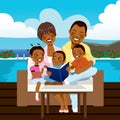 Happy african american family reading a book or looking a photo album sitting on outdoor sofa at the pool side Royalty Free Stock Photo