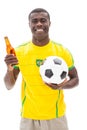 Happy brazilian football fan holding ball and beer