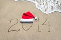 Happy new year 2014 with santa hat on sea beach sand with wave