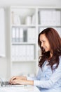 Happy woman working at her laptop attractive young sitting a desk typing on the keyboard Stock Photos