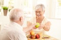 Laughing senior wife getting apple from husband