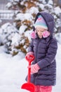 Little girl playing with red shovel in the garden