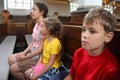 Mother, daughter and son sit on bench in Church