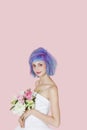 Portrait of beautiful young woman in wedding dress with dyed hair against pink background