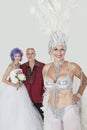 Portrait of senior showgirl with father and daughter in wedding dress against gray background