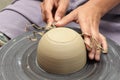 Potter's hands milling clay bowl
