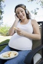 Pregnant Woman Eating Apple And Listening To Music