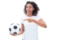 Pretty football fan in white holding ball and pointing to it