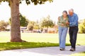 Senior Man Helping Wife As They Walk In Park Together