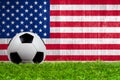 Soccer ball on grass with US flag background