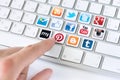 Social media communication concept hand pointing on keyboard with logotype collection of well known network brand s placed on Royalty Free Stock Photography