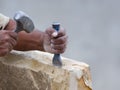 Stone mason chiseling a block of stone