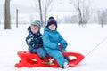 Two little siblings having fun on sledge on winter snow day