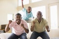 Two men and young boy in living room cheering