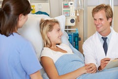 Doctor With Nurse Talking To Teenage Female Patient In Bed Stock Image