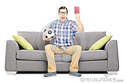 在拿着球和给一个红牌的沙发的愤怒的足球迷 
