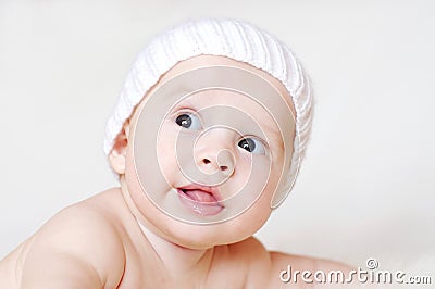 4个月的微笑的婴孩年龄在白色的编织了帽子 库