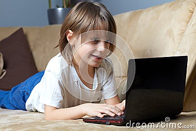 6 year old boy lying on the sofa with his laptop