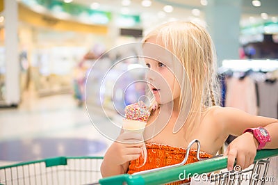 Adorable girl eat fruit ice cream with rainbow sprinkles in shop