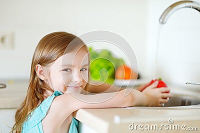 Adorable girl washing vegetables in a kitchen