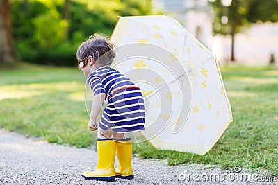 Adorable little child in yellow rain boots and umbrella in summe