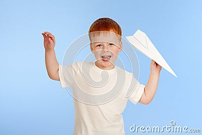 Adorable red-haired boy with paper plane model