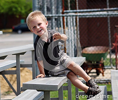 Adorable Toddler Boy sitting on the bleachers at a baseball game