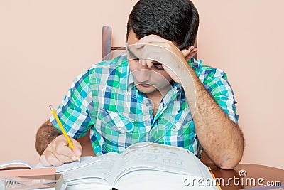 Adult hispanic man studying and writing on a notebook