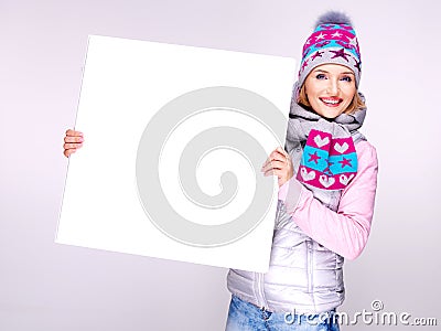 Adult smiling woman in winter hat holds the white banner