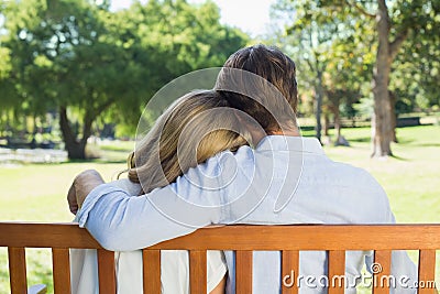 Affectionate couple relaxing on park bench together
