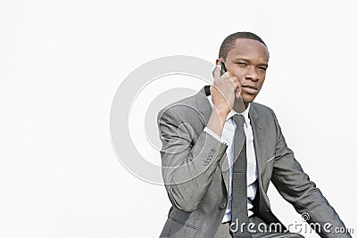 African American businessman conversing on cell phone over white background