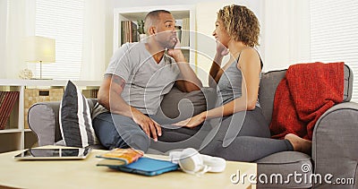 African American couple talking together on couch