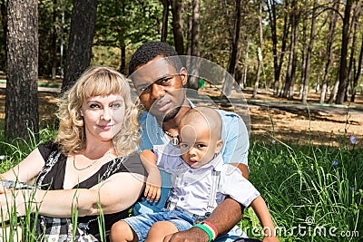 African American happy family: black father, mom and baby boy on nature.